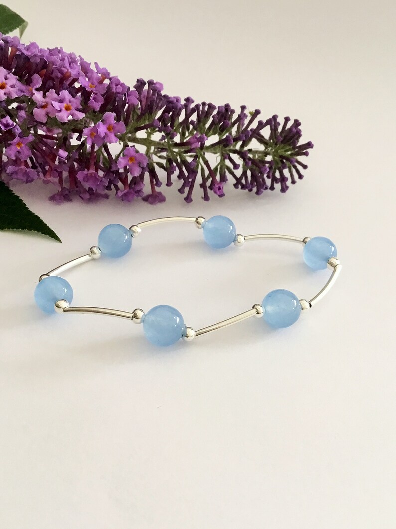 May include: A delicate bracelet with a silver chain and light blue gemstone beads.