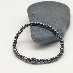 May include: A black hematite beaded bracelet with a larger bead in the center.