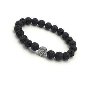 Può includere: Braccialetto con perline di roccia lavica nera con un ciondolo argentato a forma di spirale.