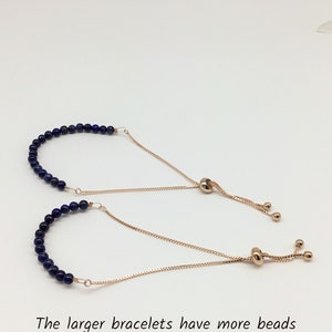 May include: Two adjustable bracelets with a gold chain and blue gemstone beads. The larger bracelet has more beads.