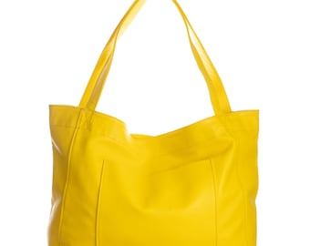 May include: A bright yellow tote bag with two long handles and a rectangular pocket on the front. The bag is made of a smooth material and is set against a white background.