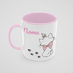 Puede incluir: Una taza de cerámica blanca con un borde y un asa de color rosa. La taza presenta una ilustración en blanco y negro de un gato con un lazo rosa, y la palabra "Nome" en letras rosas. También hay huellas de patas negras en la taza.