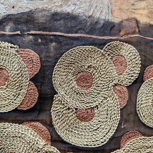 May include: Black sheer fabric with embroidered circles in beige and brown. The circles are layered and have a woven texture.