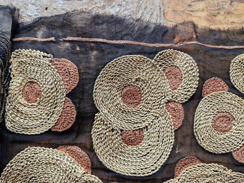 May include: Black sheer fabric with embroidered circles in beige and brown. The circles are layered and have a woven texture.