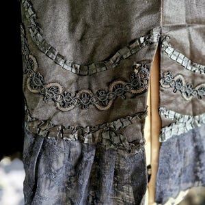 May include: A gray skirt with black lace trim and a ruffled hem. The skirt has a slit up the back.
