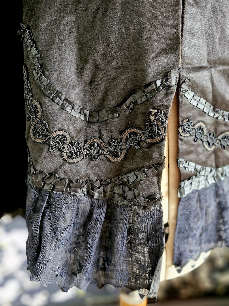 May include: A gray skirt with black lace trim and a ruffled hem. The skirt has a slit up the back.