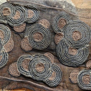 May include: Black sheer fabric with brown embroidered circles. The circles are layered and have a textured appearance.