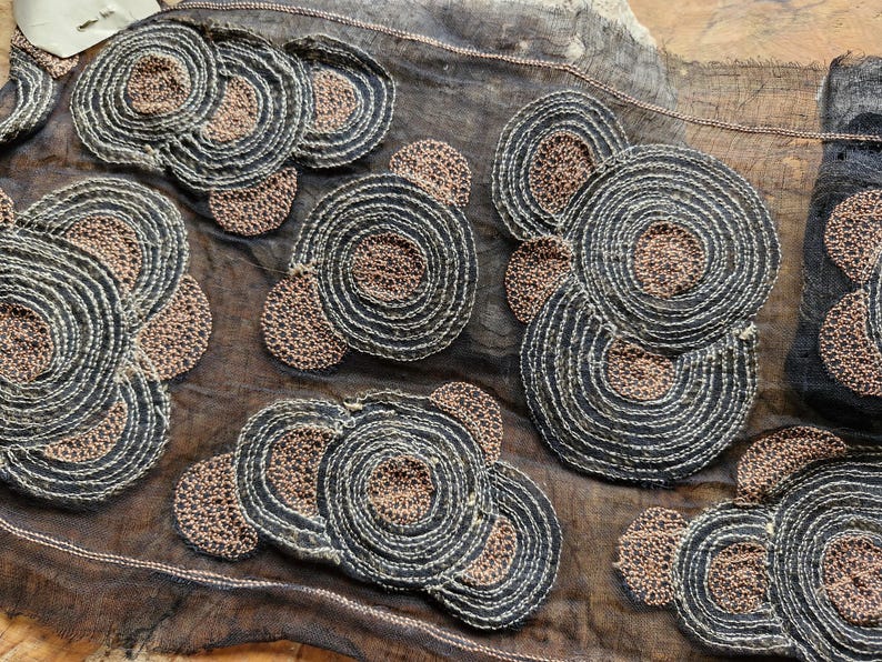 May include: Black sheer fabric with brown embroidered circles. The circles are layered and have a textured appearance.