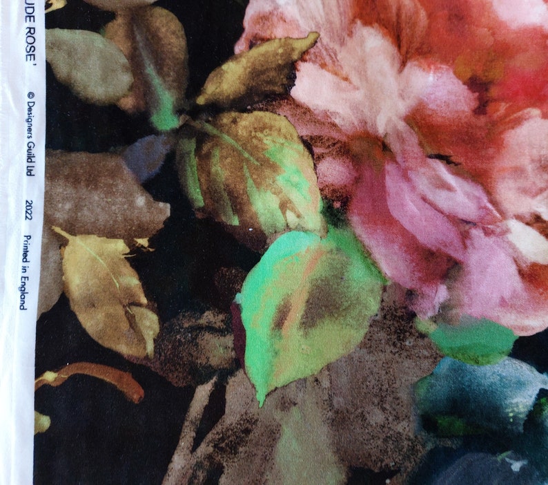 May include: A watercolor-style floral print fabric featuring large pink and red roses with green leaves on a black background. The fabric has the text "JUDE ROSE." and "&copy; Designers Guild Ltd. 2022 Printed in England" printed on the side.