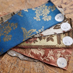 May include: Four fabric swatches with floral patterns in blue, brown, beige, and red. Each swatch has a circular label with the text "Lot 1" written on it.