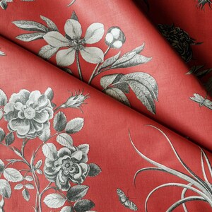 May include: Red fabric with a black and white floral pattern. The pattern features roses, leaves, and other botanical elements.