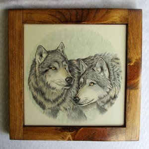 May include: A framed tile with a watercolor painting of two grey wolves looking at each other. The wolves are drawn in a realistic style with detailed fur and facial features.