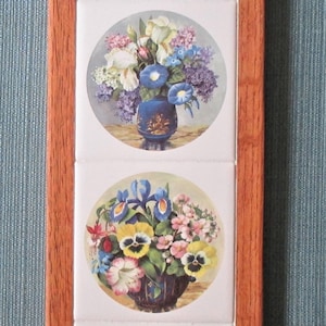 May include: A wooden framed wall art piece with four square tiles featuring floral arrangements in different colored vases. The flowers include pansies, daffodils, anemones, and irises.