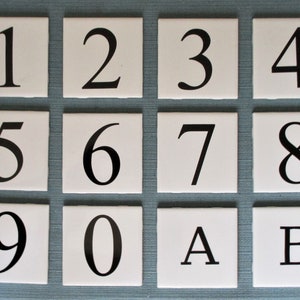 May include: White ceramic tiles with black numbers 1 through 9, 0, A, and B.