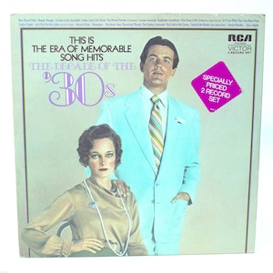 May include: A vintage record album cover featuring a man and a woman in 1930s attire. The album title is "This is the Era of Memorable Song Hits - The Decade of the '30s". The album is a two-record set by RCA Victor.