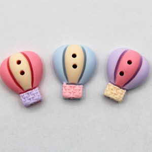 May include: Three colorful hot air balloon buttons with two holes each. The buttons are pink, blue, and purple with white accents.