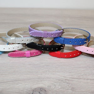 May include: A set of eight leather watch bands in various colors, including blue, white, pink, red, black, brown, purple, and gray. The bands are all the same size and have a simple, classic design.