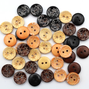 May include: A collection of round wooden buttons in various shades of brown, black, tan, and orange. Each button features two centre holes and an engraved floral pattern on the surface, showcasing a mix of solid colours and wood grain textures.