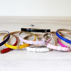 May include: A set of eight watch straps in various colours, including red, yellow, white, pink, blue, purple, and black. The straps are made of leather and have a buckle fastening.