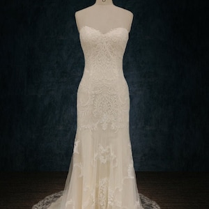 May include: A white strapless wedding dress with lace detailing and a mermaid silhouette. The dress has a sweetheart neckline and a long train.