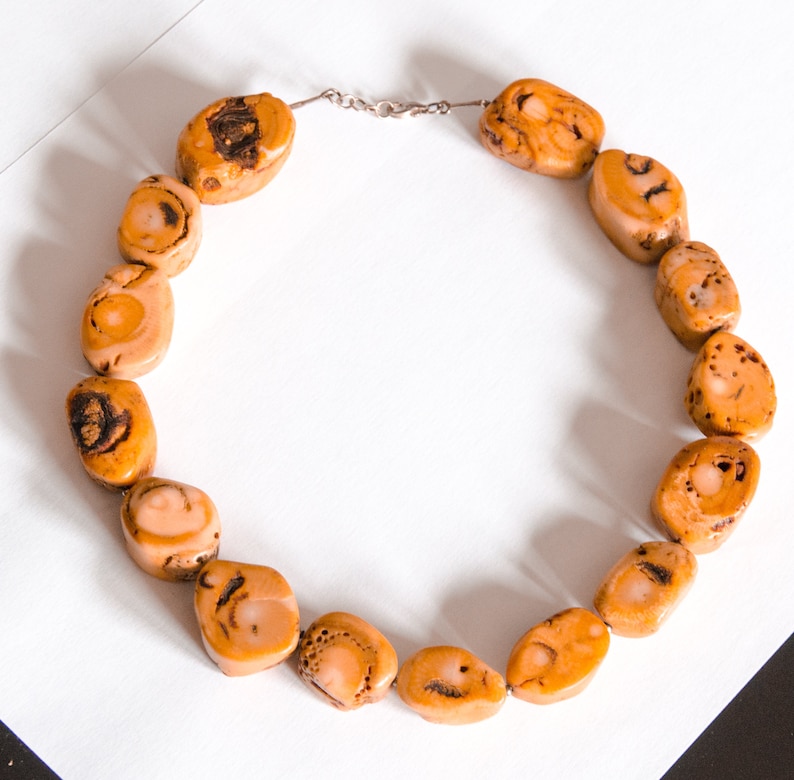 May include: A necklace made of natural brown and beige stone beads. The beads are irregularly shaped and have a mottled pattern.