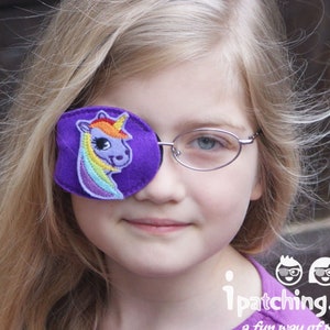 Könnte beinhalten: Ein junges Mädchen trägt eine Brille mit einem lila Augenpflaster, das mit einem Regenbogen-Einhorn verziert ist. Das Augenpflaster dient zum Abdecken eines Auges. Der Text auf dem Bild lautet "ipatching.co.uk a fun way of patching".