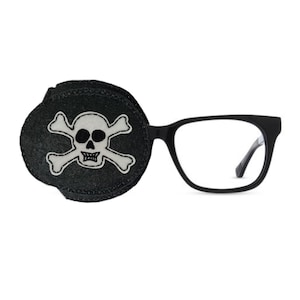 May include: Black eye patch with a white skull and crossbones design. The eye patch is attached to a pair of black framed glasses.