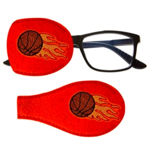Peut inclure: Deux patchs oculaires orange avec un ballon de basket et des flammes brodés. Les patchs sont conçus pour être portés sur des lunettes.
