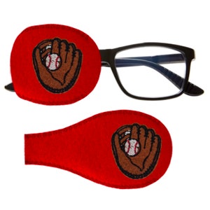 May include: A pair of red eye patches with a baseball glove and ball embroidered on them. The patches are designed to be worn over the eyes for vision therapy.
