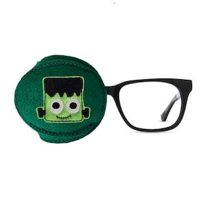May include: A green eye patch with a felt Frankenstein monster design. The eye patch is paired with black framed glasses.