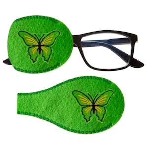 May include: Two green eye patches with a yellow butterfly embroidered on each. The patches are made of soft felt and have a decorative stitched border.