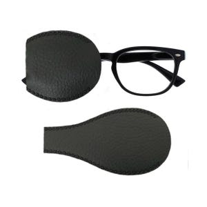 May include: Two black leather eyeglass nose pads with a stitched edge. The pads are oval shaped and are designed to be placed on the bridge of the nose.