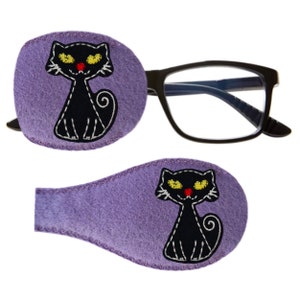 May include: Two lavender eye patches with a black cat design. The cat has yellow eyes, a red nose, and white stitching. One patch is attached to a pair of black eyeglasses. The other patch is separate.