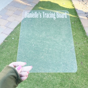 May include: A clear plastic tracing board with the text "Danielle's Tracing Board" printed on it.