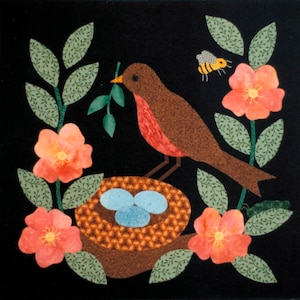 Puede incluir: Un pájaro petirrojo marrón y rojo se posa en una rama con hojas verdes y sostiene una ramita verde en su pico. El pájaro está cerca de un nido marrón con tres huevos azules en su interior. Hay flores rosas con centros amarillos en las ramas. Una abeja amarilla y negra vuela sobre las flores.