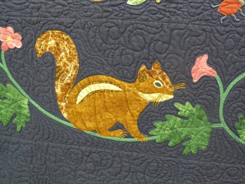 May include: A brown and white squirrel with a bushy tail is perched on a green vine with a pink flower. The squirrel is sitting on a dark blue background with a swirling pattern.