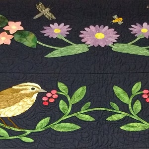 May include: A black fabric with embroidered yellow flowers, green leaves, and two brown birds on a vine with red berries.