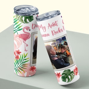 May include: Two white stainless steel tumblers with clear lids. One features a pink flamingo, tropical leaves, and flowers. The other has a photo in a frame and the text "Di My Aunt Iana Rocks!" in pink script.