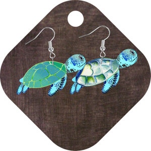 May include: A pair of silver dangle earrings featuring a blue and green sea turtle design. The turtles have a detailed shell pattern and are facing opposite directions.