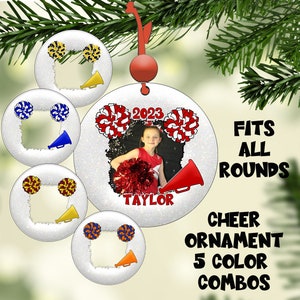 May include: A silver glitter cheer ornament with a photo frame, pom-poms, and a megaphone. The ornament has the text "2023" and "TAYLOR" on it. The ornament is available in 5 color combos.