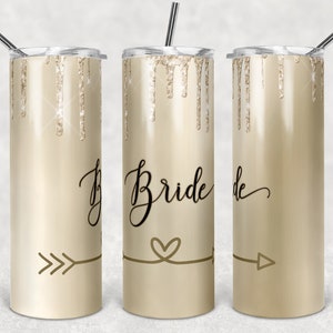 May include: Three gold glitter stainless steel tumblers with a dripping glitter effect. The center tumbler has the word "Bride" written in black cursive script with a heart and arrow design below. The left tumbler has the word "Bride" partially visible and an arrow design. The right tumbler has the word "Bride" partially visible and an arrow design.