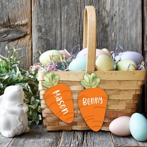 May include: A wicker basket filled with pastel Easter eggs and two carrot-shaped place cards. The place cards are decorated with green leaves and the names "Mason" and "Benny".