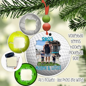 May include: Set of five white, round, personalised Christmas baubles with a sports theme. The baubles feature a golf ball, tennis ball, hockey puck, volleyball, and a pickleball. Each bauble has a space for a photo and text. The baubles are decorated with a white, glittery snow effect. The text on the baubles reads "2023", "MASON & LUCAS", and "All 5 included - add Photo and words".