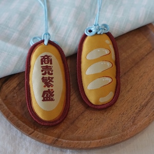 Omamori de pan para finanzas. "¡Hagamos este pan!", amuleto protector.