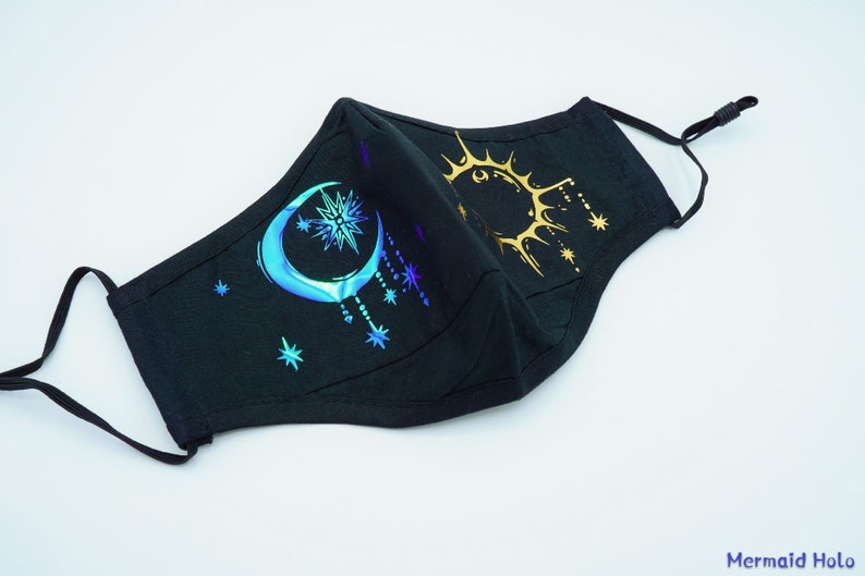 May include: Black face mask with a crescent moon and star design in iridescent blue and a sun design in gold foil.