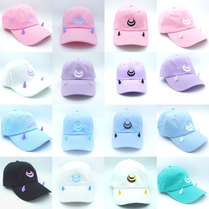 May include: A set of 12 baseball caps with a crescent moon design and small horns on the sides. The caps are in various colors, including pink, white, light blue, purple, black, and teal.
