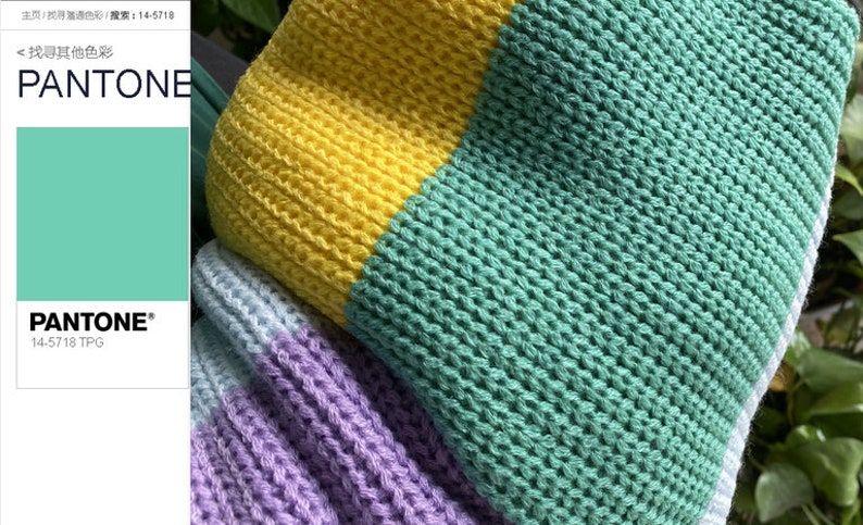 May include: A close-up of a knitted fabric with stripes of yellow, light blue, purple, and green. The fabric is textured and has a loose weave.