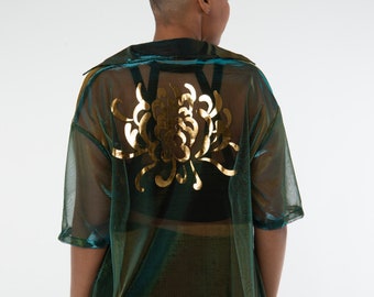 Puede incluir: Una camisa de malla transparente de color verde azulado y dorado con un diseño floral dorado en la espalda. La camisa tiene cuello y mangas cortas.