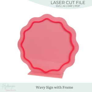 May include: A pink wavy sign with a red frame, standing upright on a matching base. The sign has the text "LASER CUT FILE" and file type options. The bottom of the sign reads "Wavy Sign with Frame".