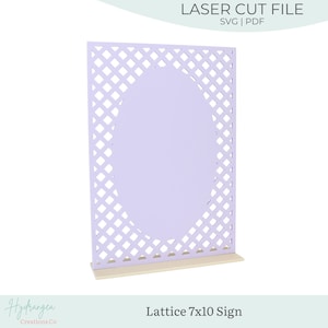Peut inclure: Panneau en treillis violet clair avec une découpe ovale, posé sur une base en bois clair. Le panneau est intitulé "Lattice 7x10 Sign" et est un fichier de découpe laser aux formats SVG et PDF.